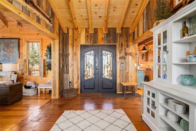 entrance foyer with french doors, beamed ceiling, dark hardwood / wood-style floors, and wood walls