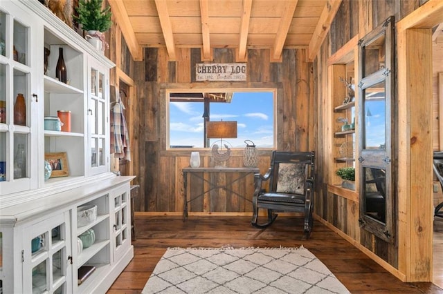 living area featuring beamed ceiling, dark hardwood / wood-style flooring, wood ceiling, and wooden walls