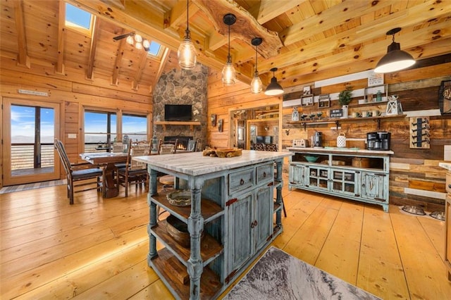 kitchen with hanging light fixtures, wooden walls, a skylight, a center island, and light wood-type flooring