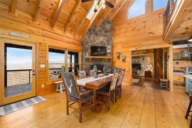 dining room featuring light hardwood / wood-style flooring, beam ceiling, a fireplace, and wood walls