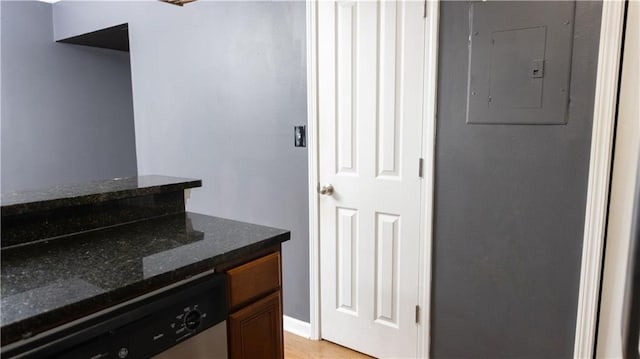 interior space with dark stone counters, electric panel, and dishwasher