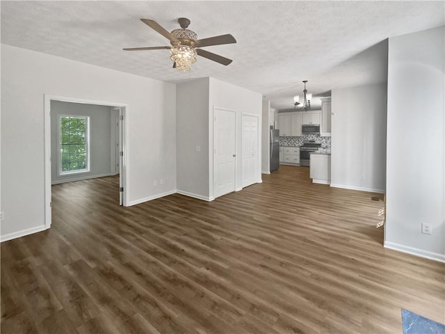 200 Eagle Glen Ct, Woodstock, GA 30189 - unfurnished living room featuring baseboards, dark wood-type flooring, a textured ceiling, a ceiling fan, and a chandelier