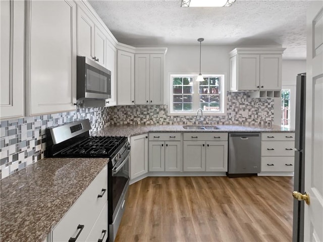 200 Eagle Glen Ct, Woodstock, GA 30189 - kitchen with appliances with stainless steel finishes, a sink, light wood-style flooring, a textured ceiling, and backsplash