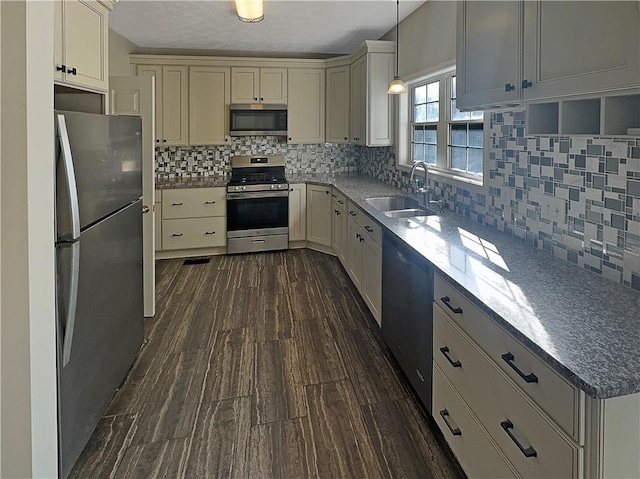 kitchen with tasteful backsplash, dark hardwood / wood-style flooring, appliances with stainless steel finishes, sink, and decorative light fixtures