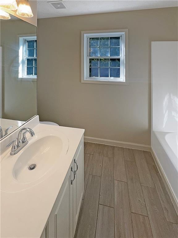 bathroom featuring vanity, hardwood / wood-style flooring, and a bath