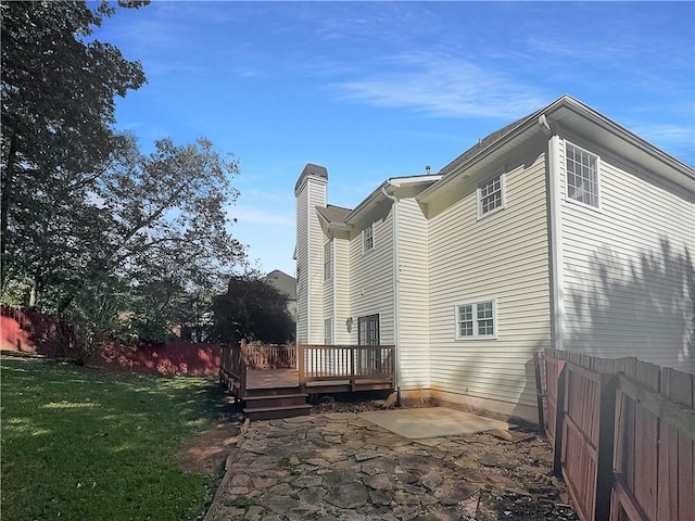 rear view of house featuring a wooden deck, a patio area, and a yard