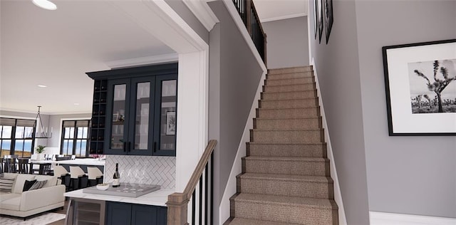 stairs with crown molding and an inviting chandelier