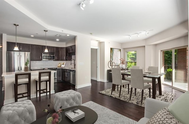 living room featuring dark wood-style floors, recessed lighting, rail lighting, and baseboards