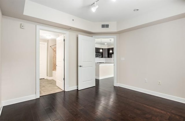 interior space with rail lighting, wood-type flooring, visible vents, and baseboards