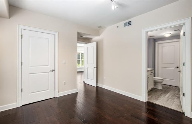 interior space featuring dark wood-type flooring, visible vents, and baseboards