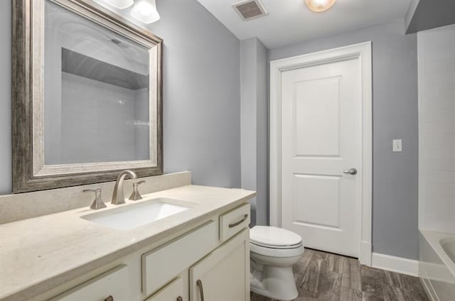 bathroom featuring visible vents, vanity, toilet, and wood finished floors