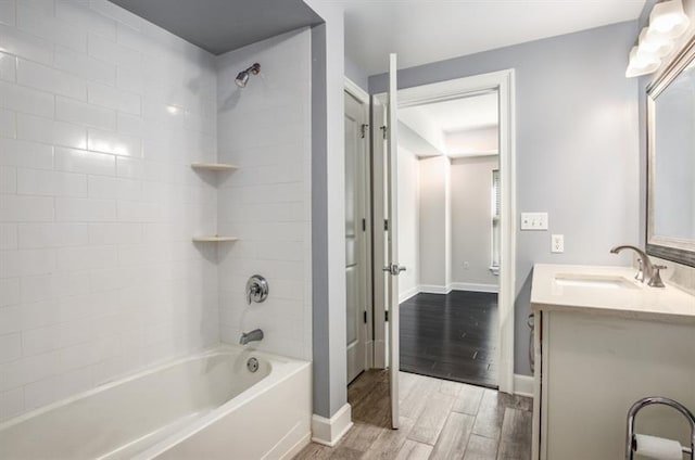 full bath with wood tiled floor, washtub / shower combination, baseboards, and vanity