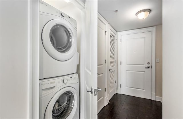 laundry area featuring stacked washer and dryer, laundry area, and dark wood-type flooring