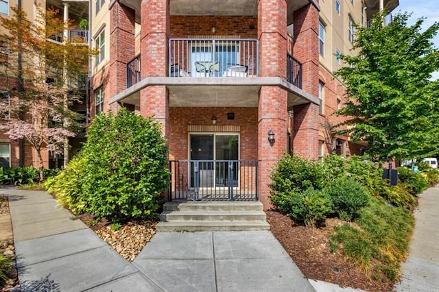 property entrance featuring a balcony and brick siding