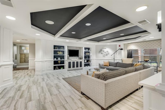 living area with built in features, visible vents, decorative columns, and light wood-style flooring