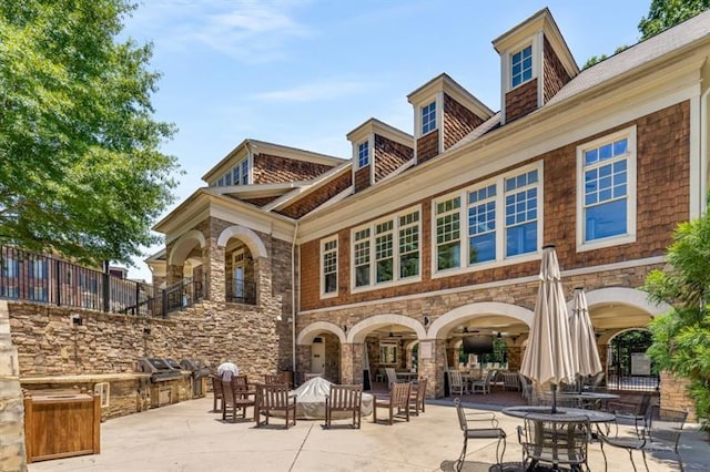 rear view of property with a patio and stone siding