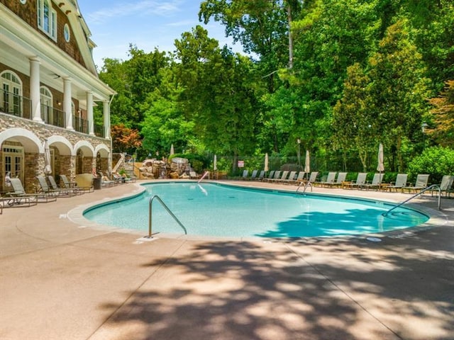 pool with a patio area and fence