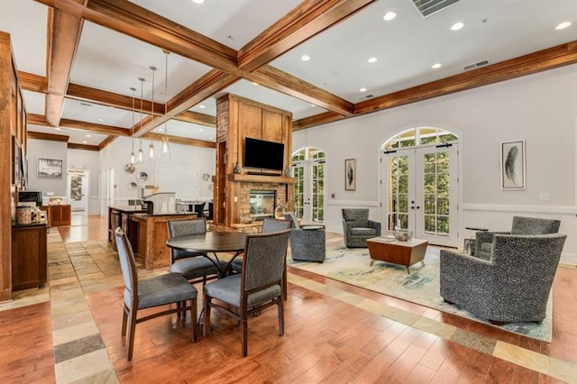 dining area featuring french doors, light wood finished floors, visible vents, coffered ceiling, and beamed ceiling