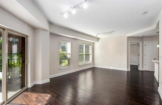 empty room with dark wood-type flooring and baseboards