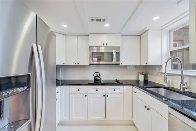 kitchen with recessed lighting, a sink, white cabinets, and stainless steel appliances