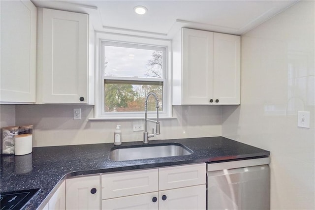 kitchen with stainless steel dishwasher, white cabinets, a sink, and dark stone counters
