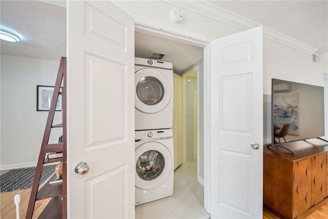 laundry area featuring baseboards, laundry area, and stacked washer / dryer