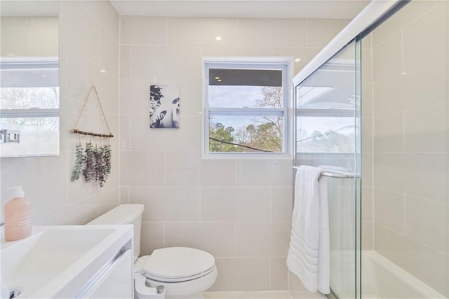 bathroom with toilet, tile walls, tiled shower, and vanity
