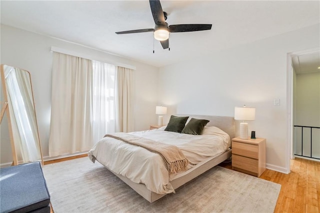 bedroom with baseboards, ceiling fan, light wood-style flooring, and attic access