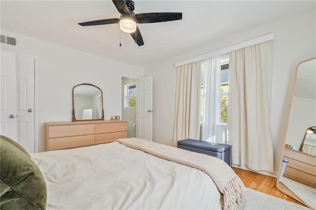 bedroom with visible vents, ceiling fan, wood finished floors, and multiple windows