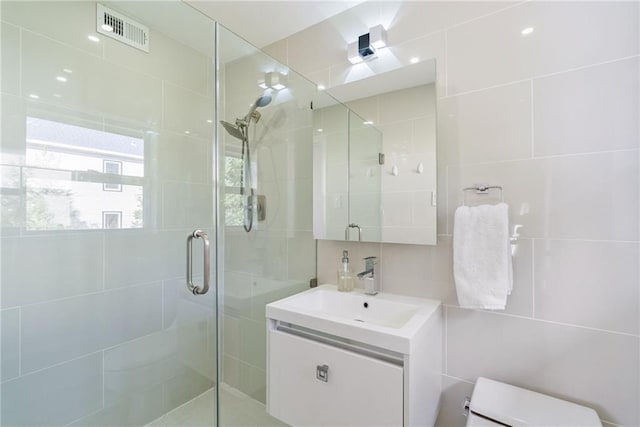 full bathroom featuring tile walls, a shower stall, and visible vents