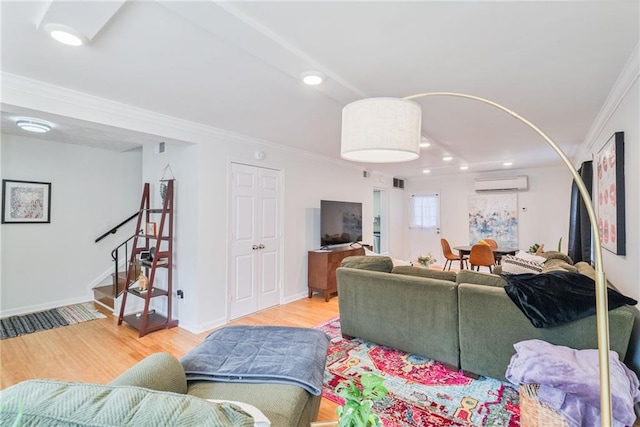 living area with visible vents, crown molding, a wall mounted air conditioner, wood finished floors, and stairway