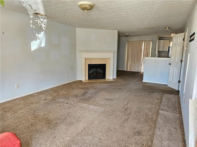 unfurnished living room featuring a fireplace with flush hearth, dark carpet, and a textured ceiling