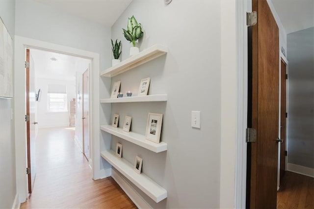 hall featuring light wood-style floors and baseboards