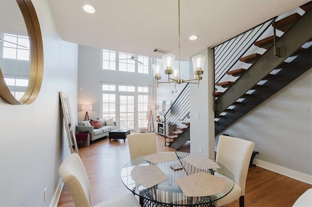 dining area featuring a healthy amount of sunlight, wood finished floors, visible vents, and stairs