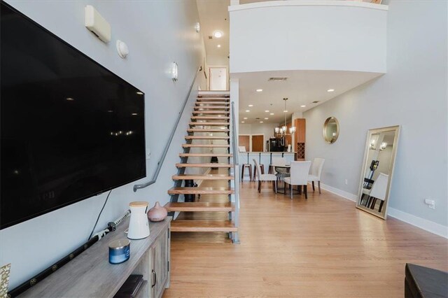 stairs featuring visible vents, baseboards, a towering ceiling, and wood finished floors