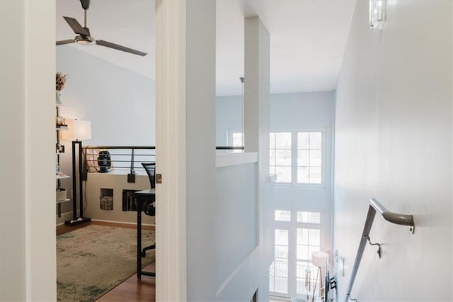 hall with wood finished floors, baseboards, and an upstairs landing