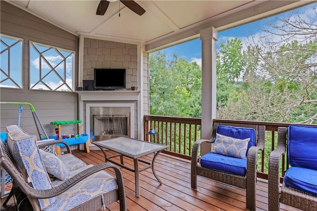 deck featuring an outdoor living space with a fireplace and a ceiling fan