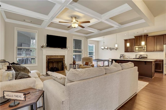 living room with a fireplace, visible vents, coffered ceiling, and wood finished floors