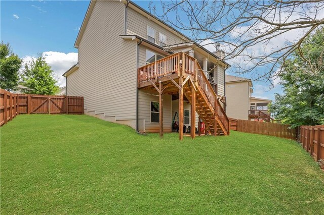 rear view of house featuring a fenced backyard, a deck, a lawn, and stairs