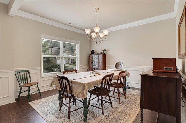 dining room with a notable chandelier, crown molding, dark wood-type flooring, visible vents, and wainscoting
