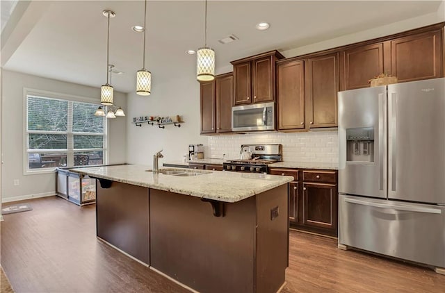 kitchen with tasteful backsplash, a sink, appliances with stainless steel finishes, recessed lighting, and dark wood-type flooring