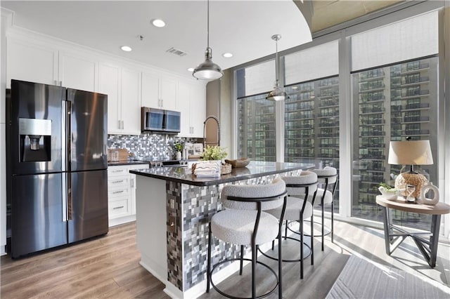 855 Peachtree St NE Unit 1703, Atlanta, GA 30308 - kitchen featuring appliances with stainless steel finishes, a wall of windows, light wood-style flooring, white cabinetry, and backsplash