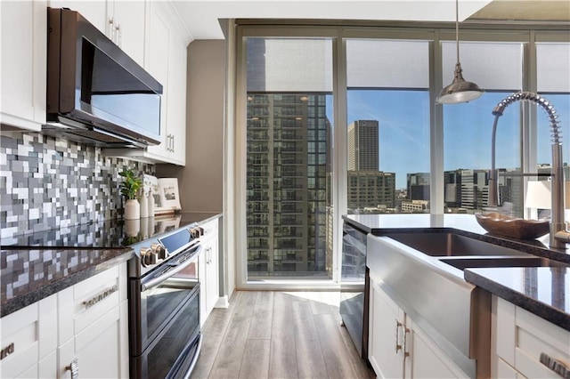 855 Peachtree St NE Unit 1703, Atlanta, GA 30308 - kitchen featuring stainless steel appliances, a sink, light wood-type flooring, backsplash, and white cabinets