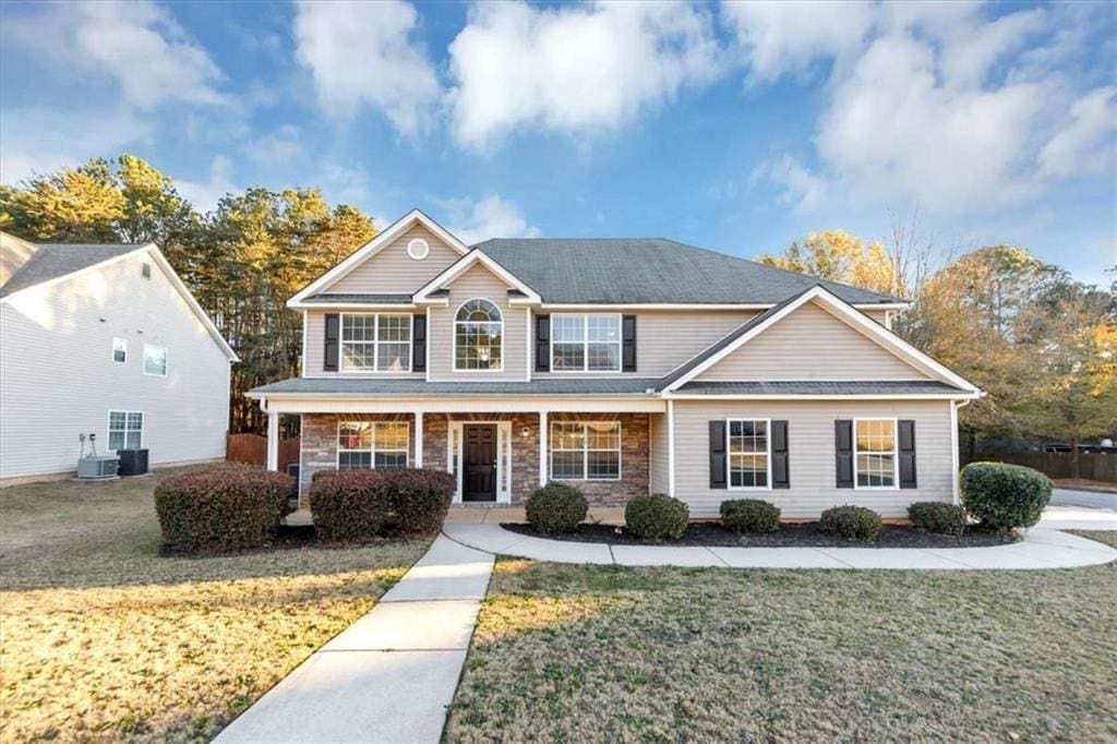 view of front of property featuring a front yard and central AC