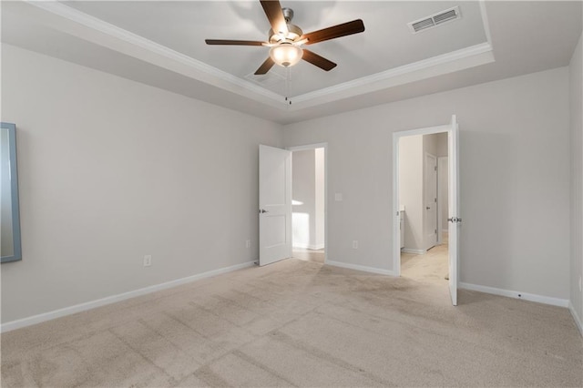 unfurnished bedroom with ornamental molding, light carpet, ceiling fan, and a tray ceiling