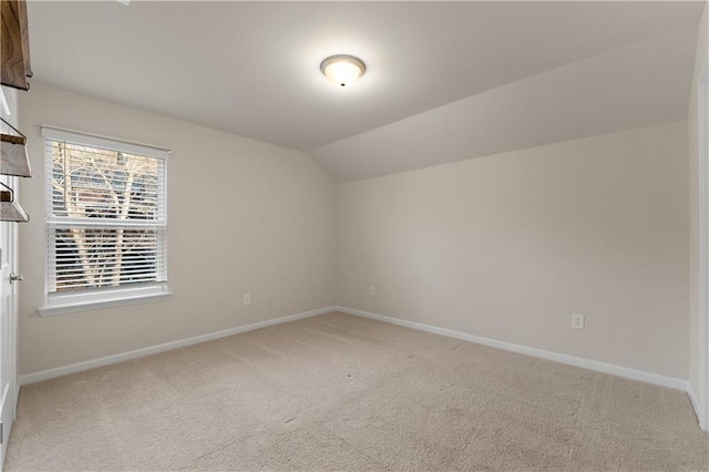 carpeted spare room with lofted ceiling