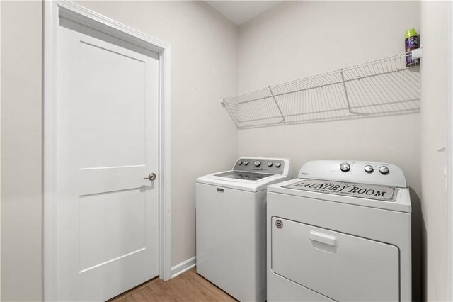 laundry area with independent washer and dryer and light hardwood / wood-style floors