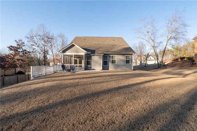 back of property with a sunroom, a patio area, and a lawn