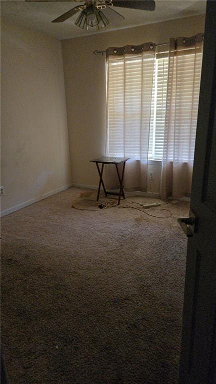 carpeted spare room with baseboards and ceiling fan