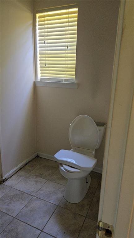 bathroom with tile patterned flooring, baseboards, and toilet
